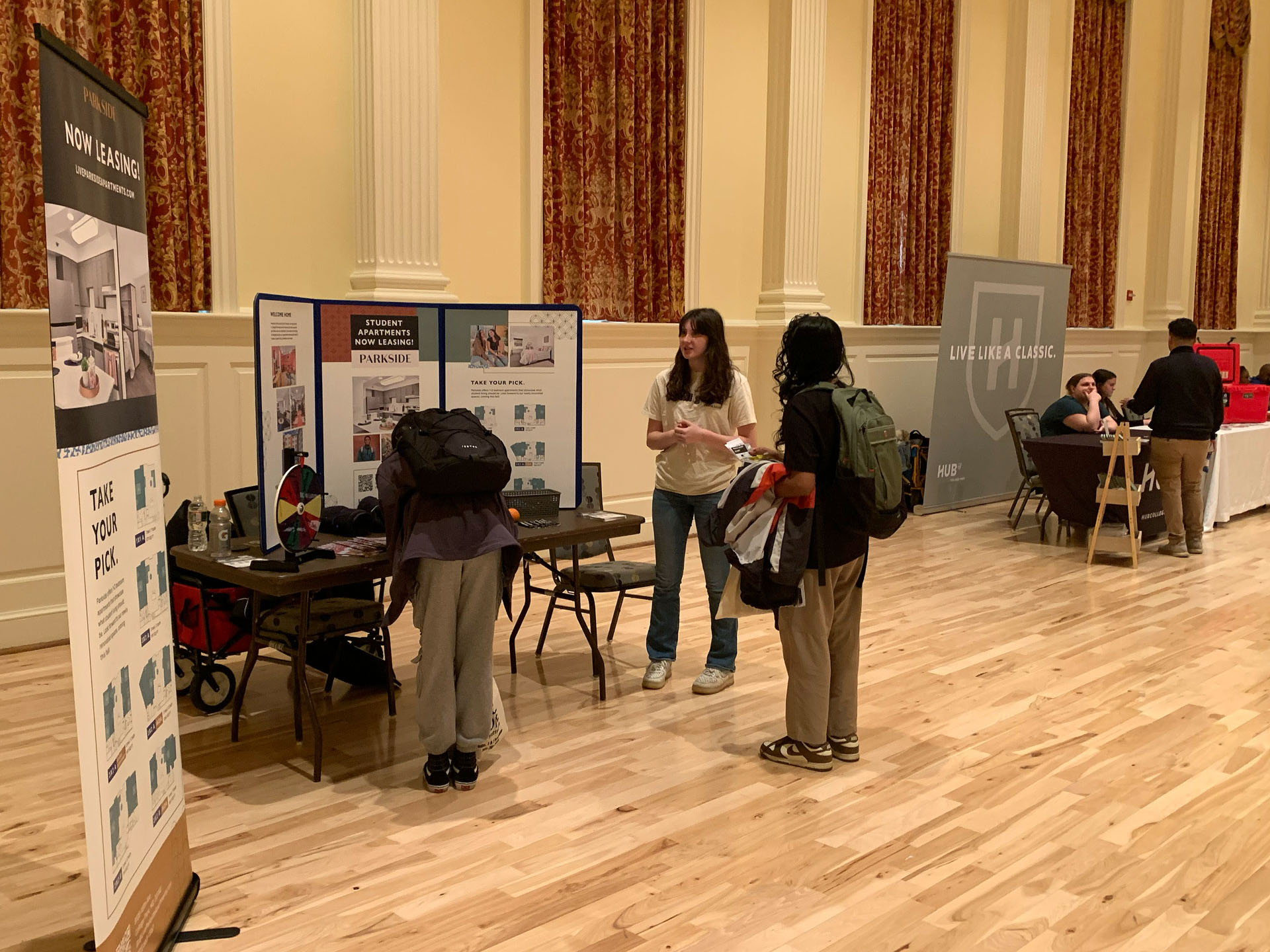 person filling out information at a table and another talking to a property representative during the fair